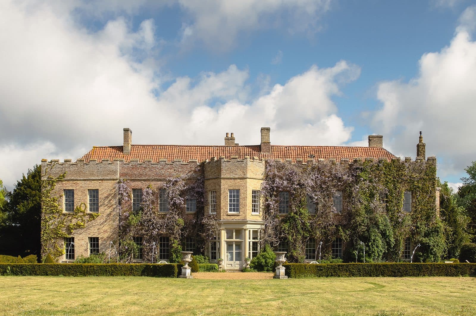 The front elevation of the estate — wisteria across five-hundred-year-old brick